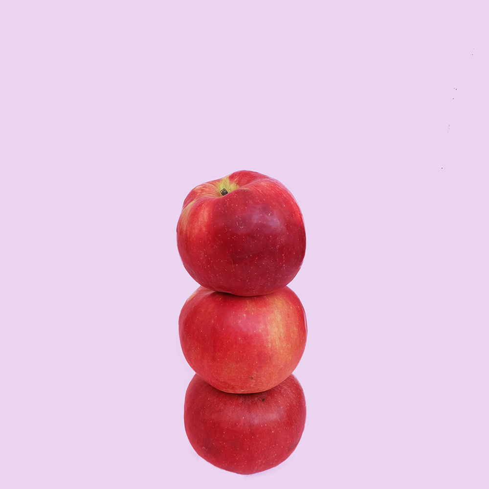 Three red apples balancing on top of one another.