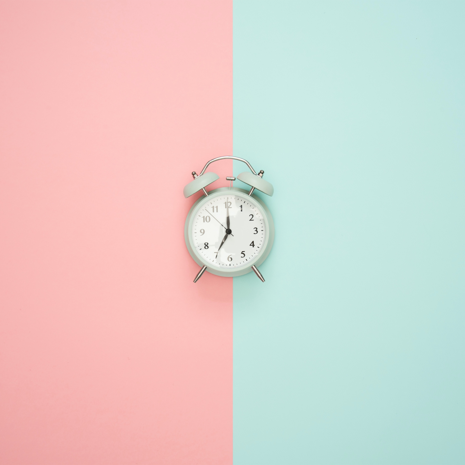 Clock against a pastel blue and pink background.