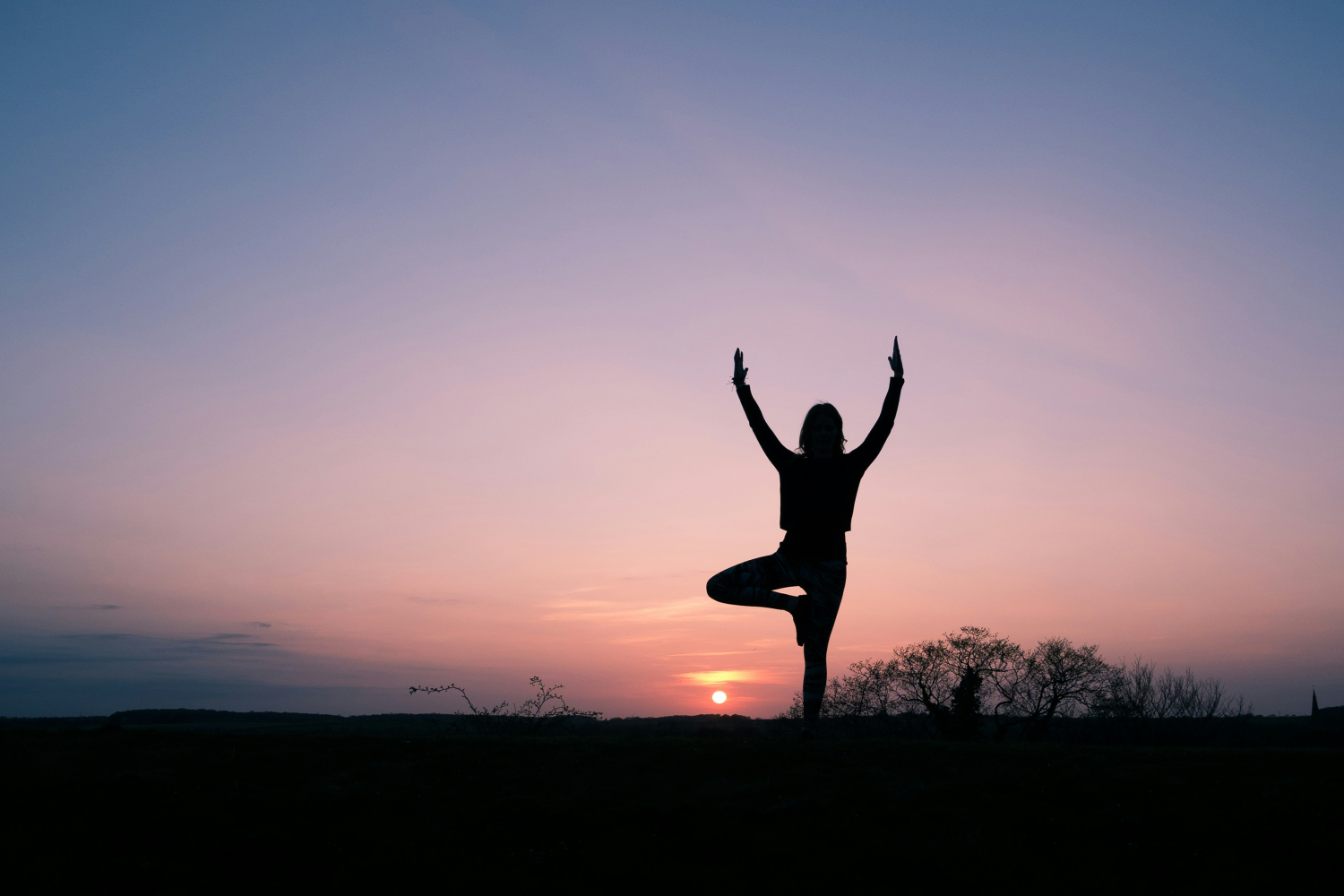 Sunset with a silhouette of someone doing yoga.