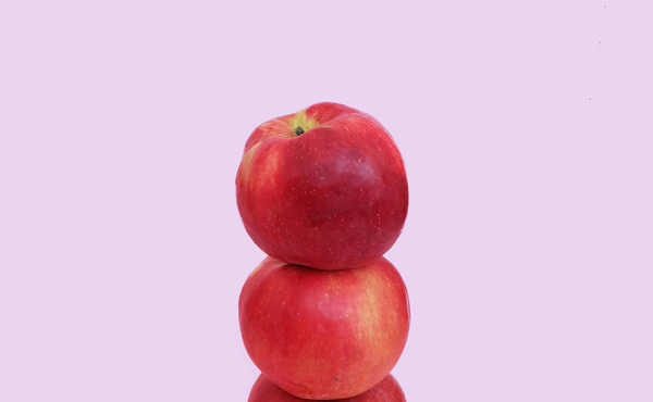 Three red apples balancing on top of one another.